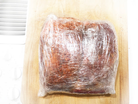 envuelva la carne de cerdo en una envoltura de plástico para marinarla y preparar deslizadores de carne de cerdo en una olla de hierro fundido de 7 cuartos