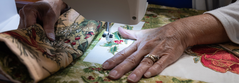 Hands guiding a quilt through a sewing machine