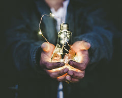 Ideas shown as a lit bulb in a businessman's hands