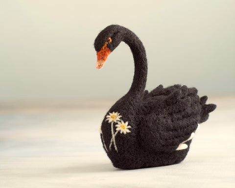 needle felted black swan with needle felted flannel flowers on its surface