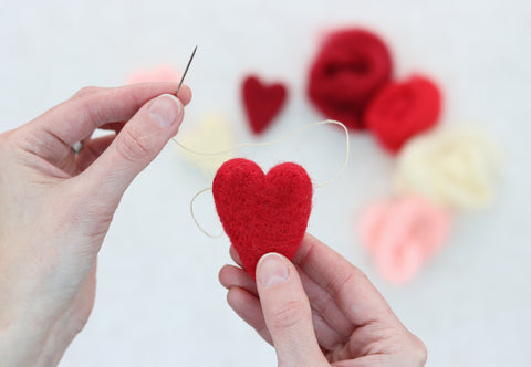 using needle and thread to make heart garland