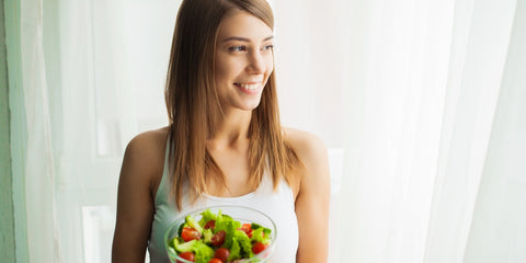 Woman holding a fresh salad in a glass bowl