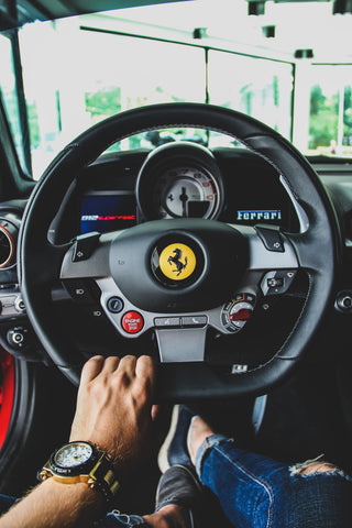 Man with luxury watch driving Ferrari