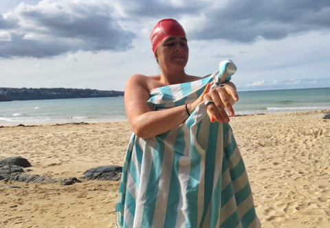 Wild Swimmer on a beach with beach towel and swim hat on