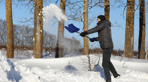 Woman shoveling snow to help fight holiday stress and get exercise in the cold weather 