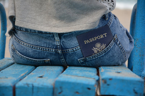 woman in jeans sitting on a wooden chair with her US passport in her back pocket