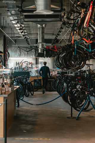 Man at the counter of a bike store with lots of bikes hanging on racks in the foreground