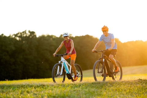 Middle aged couple riding ebikes in the setting sun