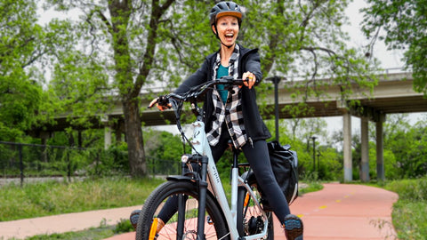 Woman with crazy grin on her face riding ebike on a cycle lane.