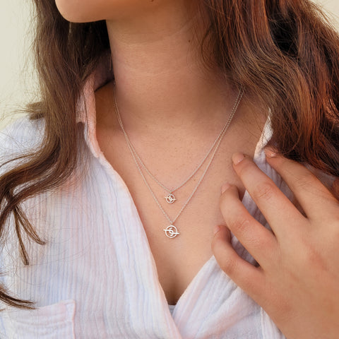 Girl with brown hair wearing two Australian solid sterling silver Joya Jewellery logo pendants on necklace