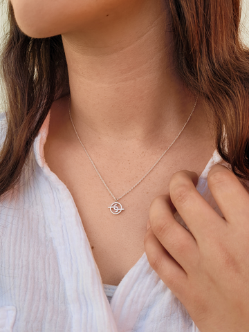 Women with brown hair wearing an ethically made joya sterling silver logo/ signature necklace
