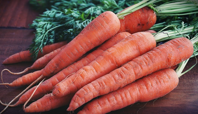 A pile of carrots with the greens on top