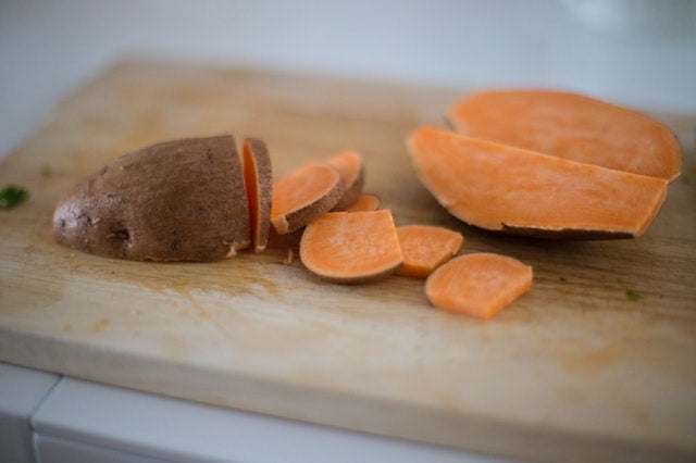 A diced sweet potato on a wooden cutting board