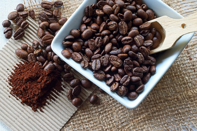 Coffee beans in a bowl beside ground coffee