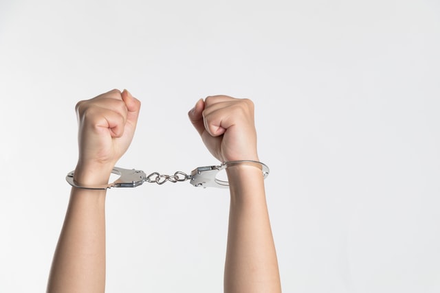 Two hands in the air in handcuffs