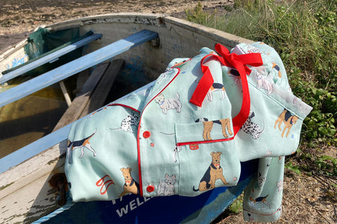 Tessie Poppy Dog Pyjamas folded on a rowing boat in Wells next the sea in Norfolk. 100% tencel pyjamas feature a dog print design.