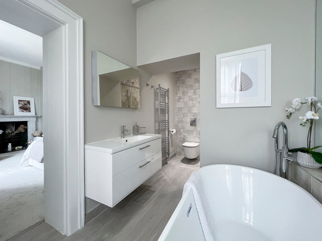 Master bedroom bathroom in a timeless and neutral scheme with a free standing bath and wall hung vanity unit