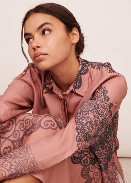 Woman wearing a lace print shirt in dusky pink and navy