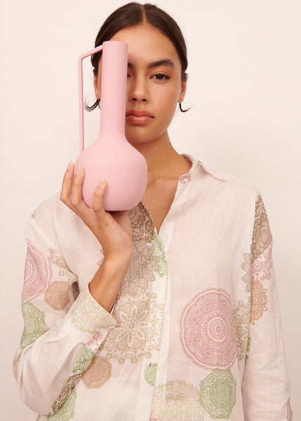 Woman wearing a doily print shirt holding a pink vase