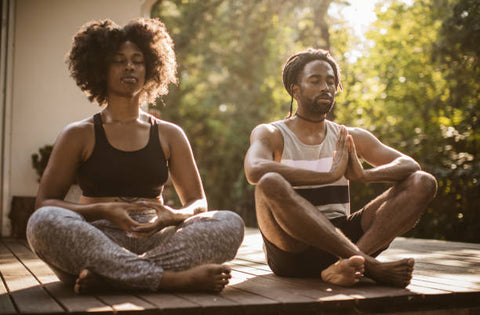 Black male and female peacefully mediating on their front porch surrounded by nature 