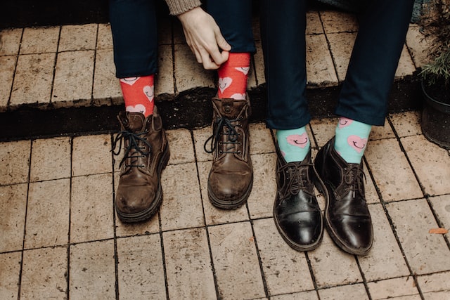 photo of two people wearing colorful socks and dress shoes sitting on stairs