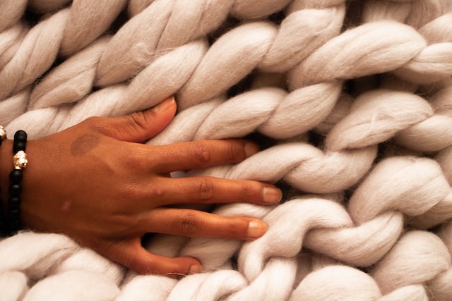 a photo of a hand lightly touching large strands of white wool