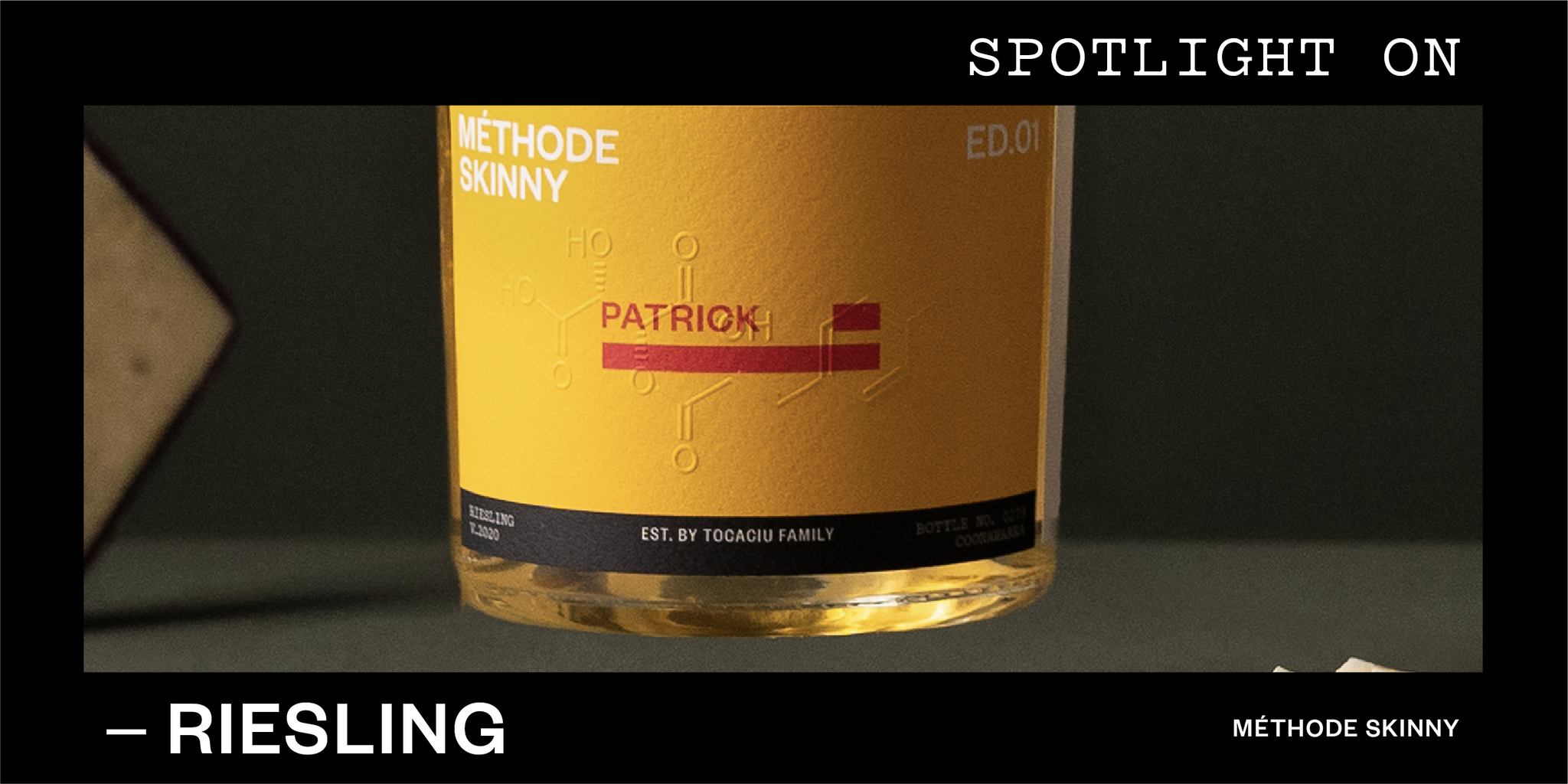 Bottom half of a bottle of white wine against a dark background. Text reads 'Spotlight on Riesling'. 