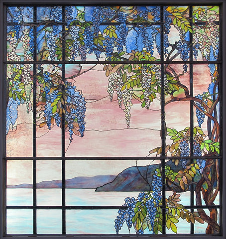 An idealised coastal view with a cascade of purple flowers against a blush punk and blue sky. In the distance, a rock juts into the ocean. Tiffany window in his house at Oyster Bay, New York (1908)