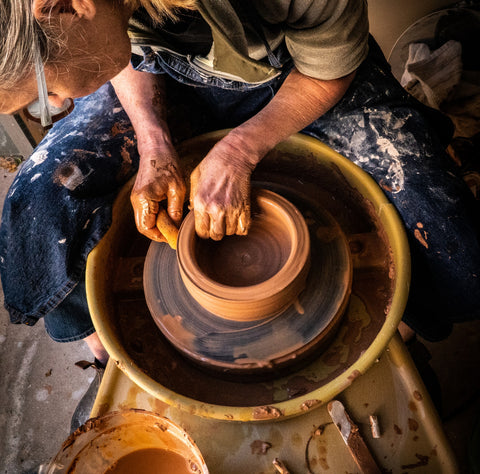 Person at a potter's wheel making a clay pot