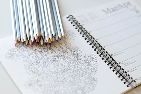 Stack of colouring pencils on top of a colouring book with an animal design