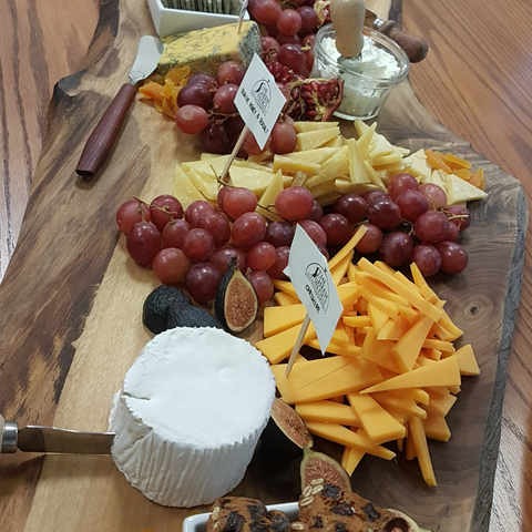 A completed charcuterie board with labels beside each type of cheese to show what type of cheese it is.