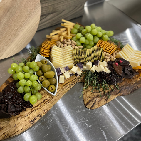 Completed charcuterie board with a variety of cheeses, meats, fruits, nuts, and crackers.