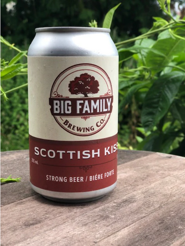 Can of Big Family Brewing Co.'s Scottish Kiss strong beer, set on a wooden table with plants in the background.