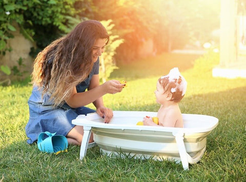 Toddler and mother playing in a bathtub outside