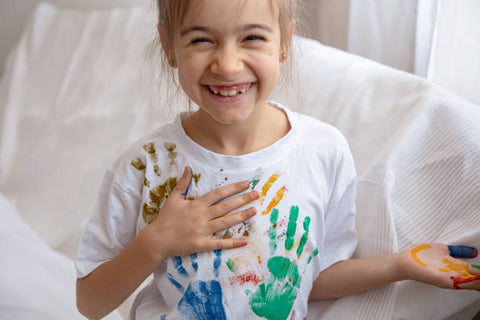 nena somrient amb taca de pintura a la roba