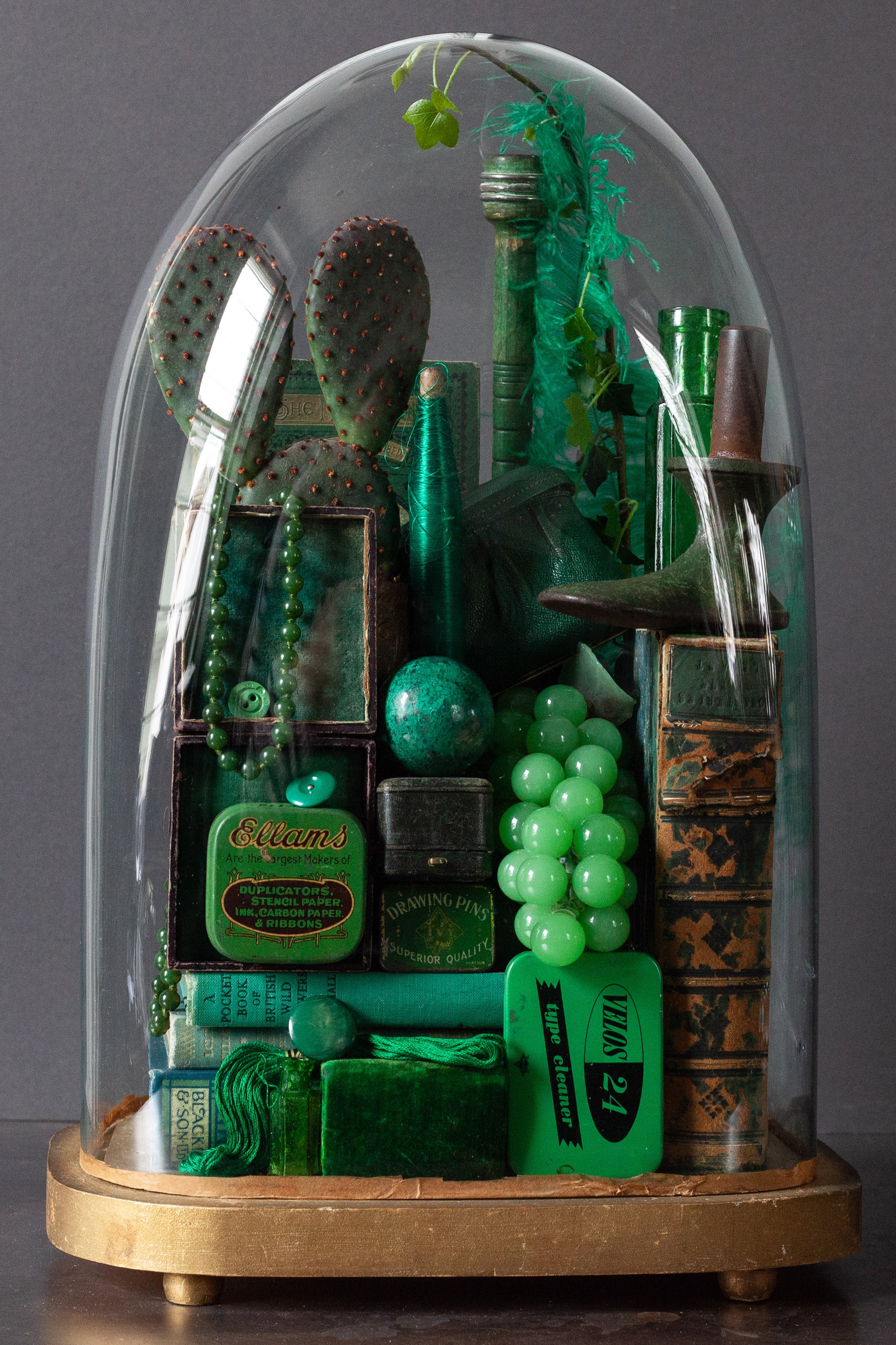 Collection of green vintage curiosities in glass dome