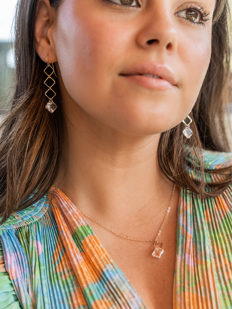 Woman in a green and pink patterned top wears gold and crystal jewelry by Kenda Kist