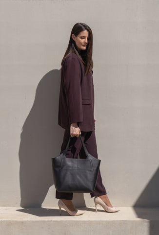 mujer luce moda bolso negro al sol