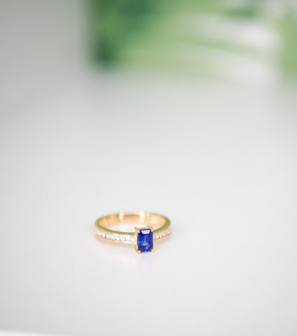 a close up of a sapphire engagement ring set in yellow gold and diamonds