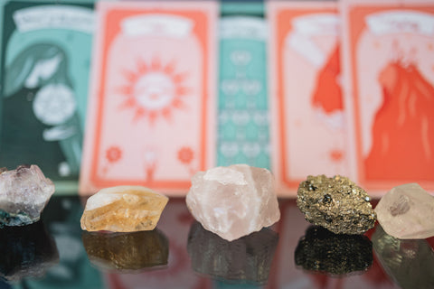 a line up of crystals with tarot cards out of focus in the background