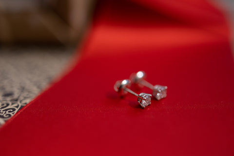 a pair of diamond studs sit atop a red ribbon