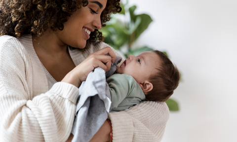 Mum wiping infant with muslin swaddle cloth