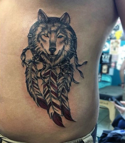 Tatouage Attrape-rêve Capteur de rêve tête de loup yeux vairons anneau en bois plume rouge