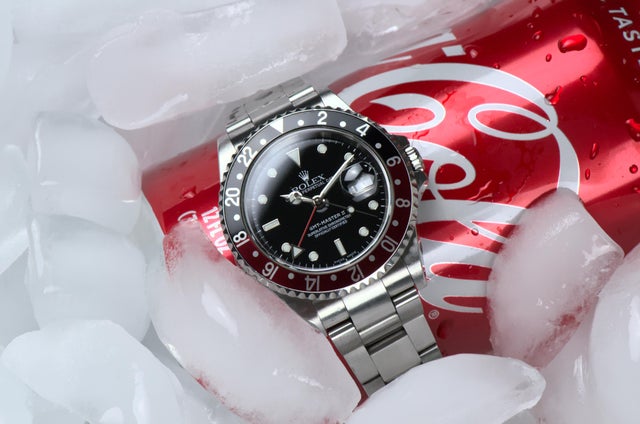 vintage rolex gmt master coke laying on a can of coke on ice