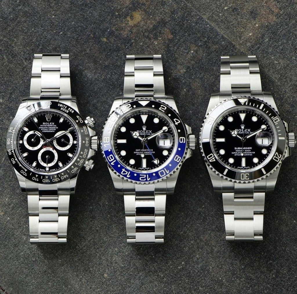 rolex daytona, gmt master ii, and submariner laying on a table