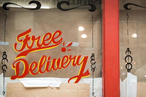 The words free delivery hand painted on a storefront window