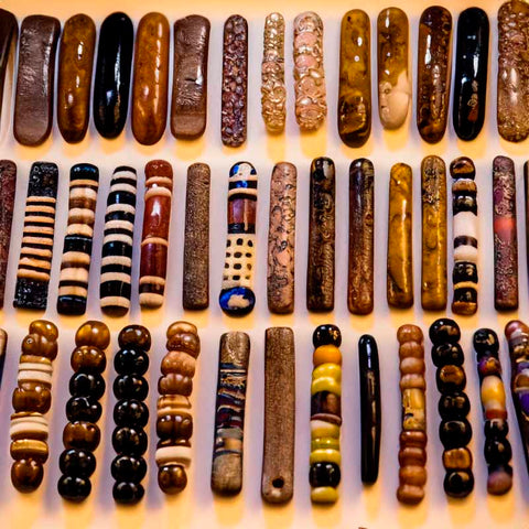 A collection of ancient bead jewelry displayed in a museum setting, showcasing diverse cultures and historical periods