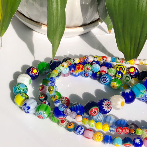 A collection of colorful beads made from recycled glass and ethically sourced stones laid out on an artisan's work table