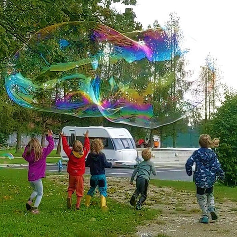Kinder fangen eine fröhlich, bunte Riesenseifenblase