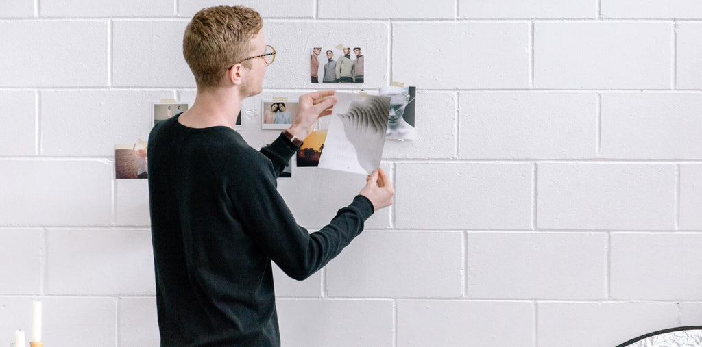 a man holding paper in front of the wall